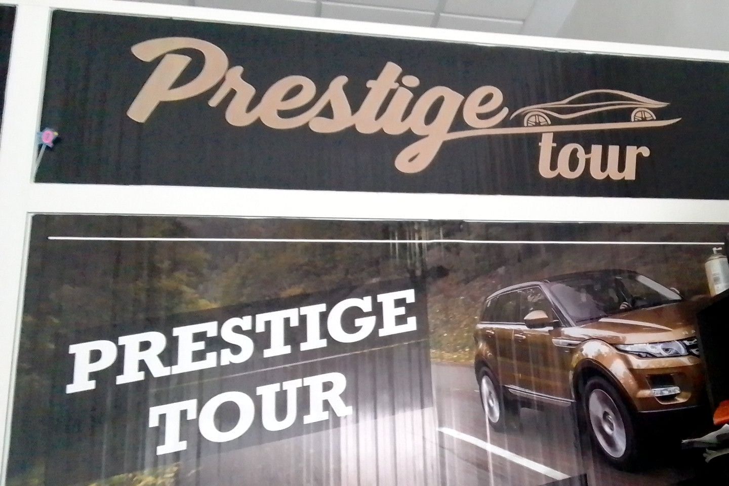 À l'intérieur de l'agence : le panneau doré « Prestige tour » au-dessus d'une affiche