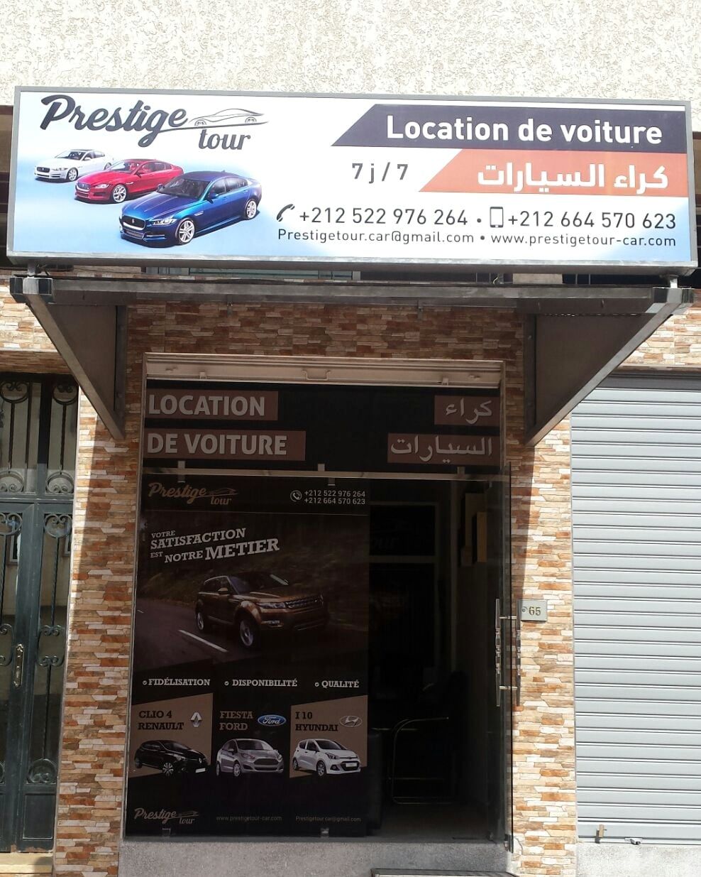 La façade de l'agence Prestige Tour, N° 65, avec l'enseigne lumineuse et les affiches de la porte